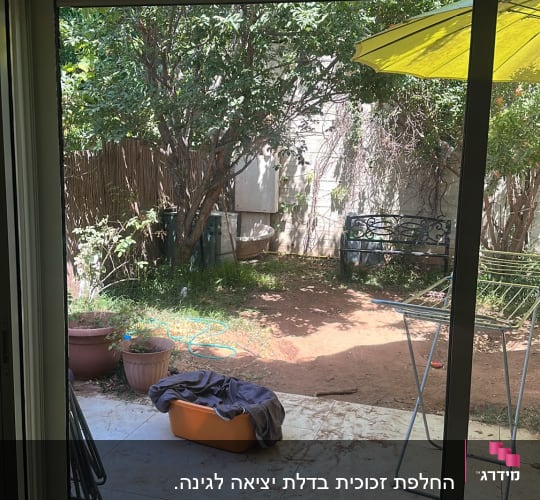 נוף גינה דרך דלת זכוכית עם שמשיה צהובה
